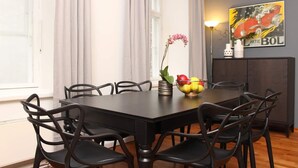 Un coin repas avec une table et des chaises en bois foncé, un panier de fruits et un vase décoratif avec des fleurs.