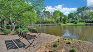 Un parc avec un étang, des bancs et un pont.