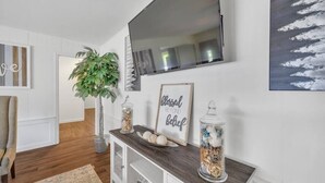 Un salon moderne avec une console en bois, une plante en pot, des bocaux décoratifs et un panneau encadré.