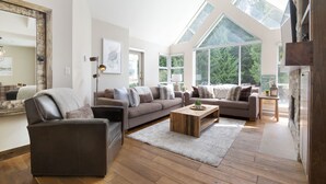 Un salon spacieux avec un haut plafond, de grandes fenêtres et une cheminée accueillante.