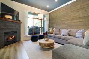 Un salon moderne avec une cheminée, une grande fenêtre, un canapé gris et une table basse ronde.