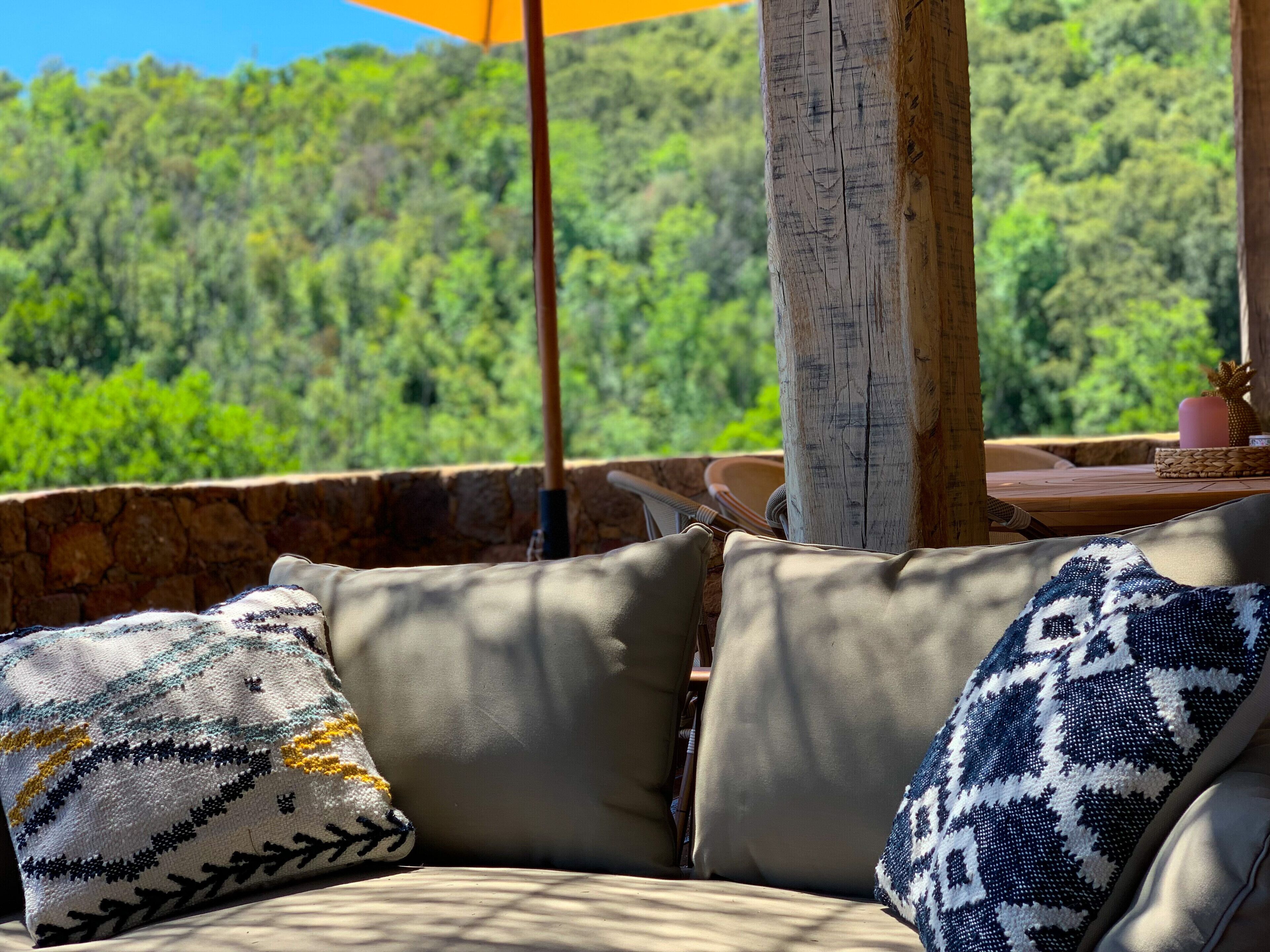 A cozy outdoor seating area with cushioned sofas and a stone wall backdrop.