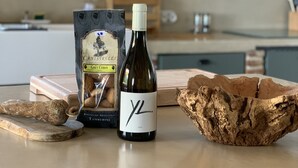 Una encimera de cocina con una botella de vino, un paquete de galletas y un trozo de madera.