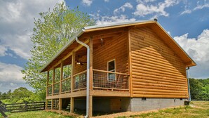 Eine Blockhütte mit einem Balkon, einer Holzterrasse und einem großen Fenster.