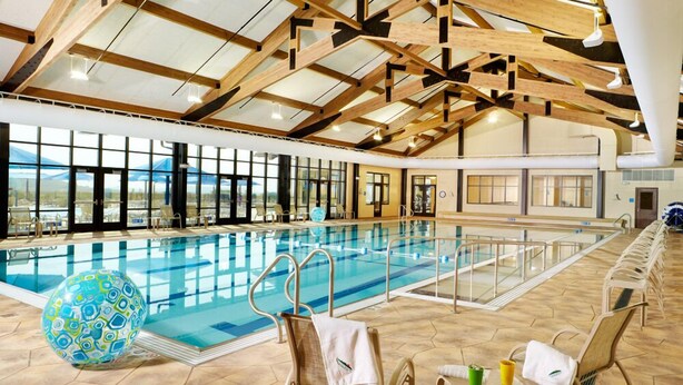 Ein Hallenbad mit hoher Decke und natürlichem Licht durch große Fenster.