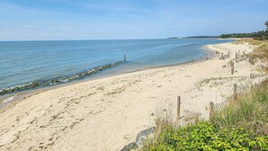 Una spiaggia sabbiosa con una recinzione in legno e vegetazione.
