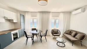 Cozinha moderna com área de refeições, um sofá e vista para o mar.