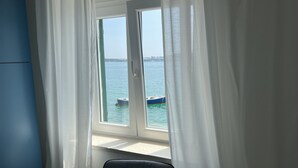 Quarto com janela dando para a água e um barco.