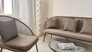 Uma sala de estar moderna com sofá, poltrona e mesa de centro de vidro.