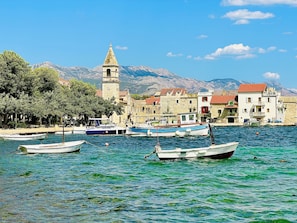 A coastal town with a prominent tower, boats docked along the waterfront, and buildings with red-tiled roofs. - Spacious vacation apartment with a view of the sea (Kaštel Sućurac)