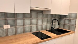 Eine moderne Küche mit einer Holz Arbeitsplatte, einem schwarzen Spülbecken und einer Spritzschutzwand mit Rillenmuster.