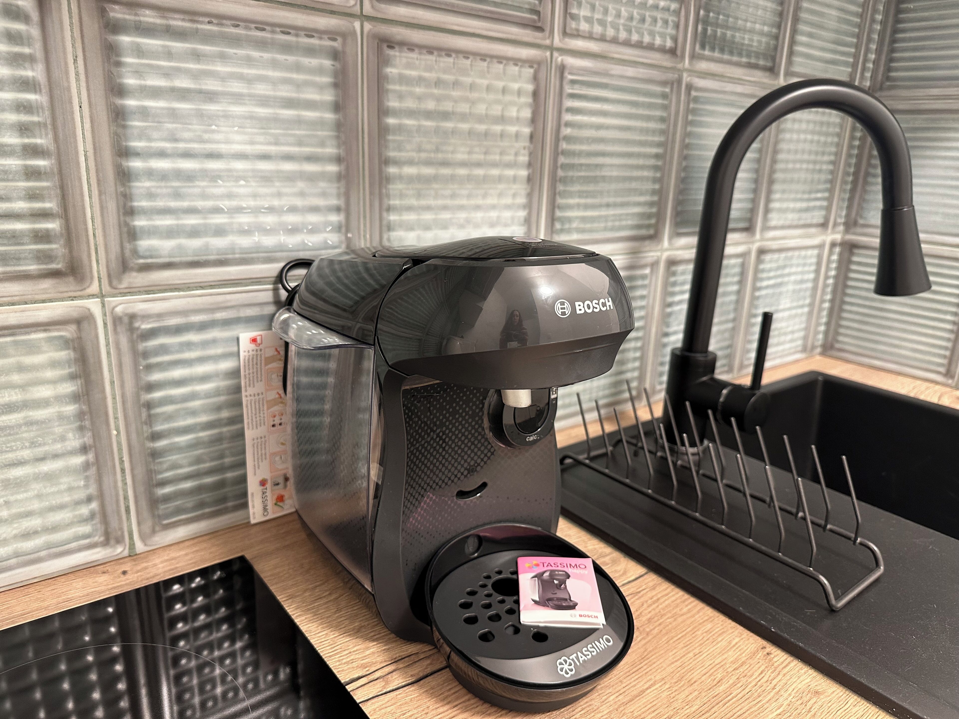 Una cafetera Bosch con un portacapsulas Tassimo sobre una encimera de cocina.