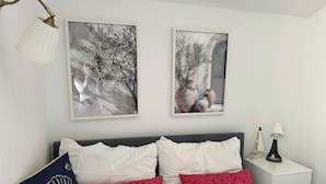 Ein Schlafzimmer mit einem Bett, zwei Wandlampen und zwei gerahmten Bildern.