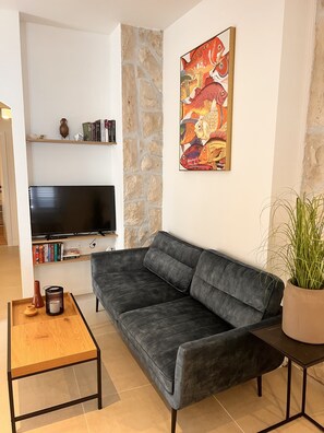 A living room with a grey sofa, a TV, a bookshelf, and a painting. - Großzügige Wohnung mit Meerblick (Kaštel Sucurac)
