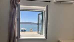 Et værelse med et vindue, der ud til et vandområde, en båd og en stengrunding.