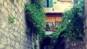 Un estrecho callejón con paredes de piedra y un edificio con balcón.