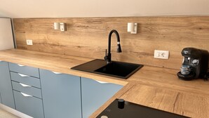 Una cocina moderna con salpicadero de madera, un lavamanos negro y una cafetera Bosch.