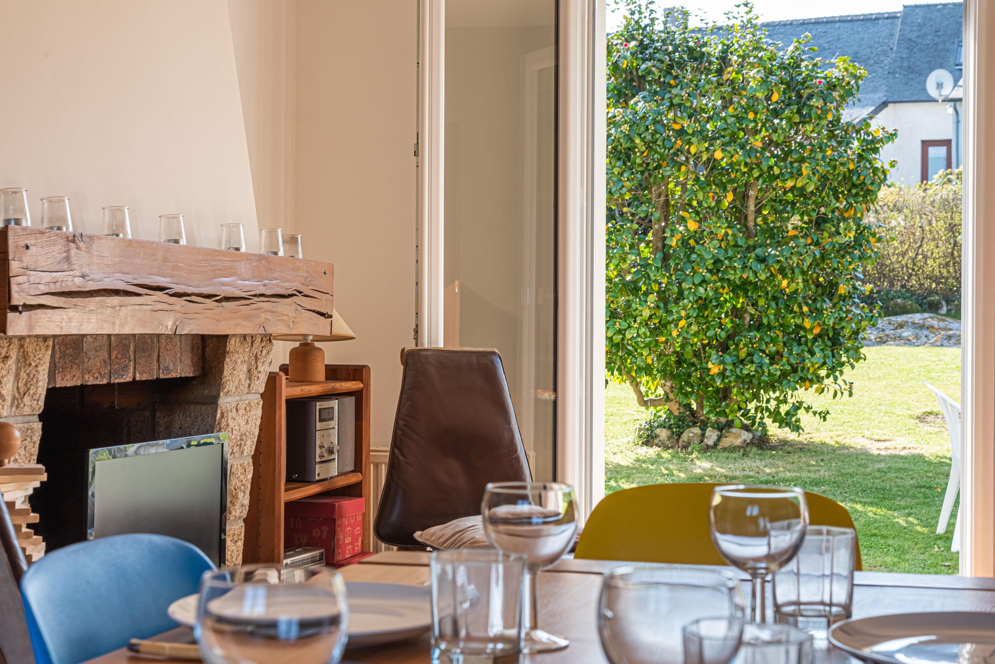 Un comedor con una mesa de madera rústica, sillas y vistas a un jardín exuberante a través de un ventanal.