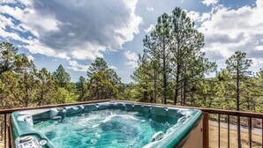 A hot tub on a deck with a view of trees and sky.