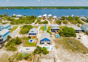 A coastal residential area with houses, a swimming pool, and a view of the sea. - Coastal Retreat | Private Pool | Pet Friendly | Walk to Beach (Gulf Shores)