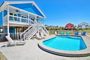 A two-story building with a swimming pool, a covered deck, and a staircase leading to the upper floor.