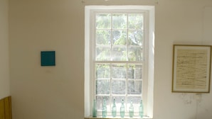 A room with a wooden ceiling, a table with a white tablecloth, two chairs, a bed with white bedding, and a window with bottles. - charming house (Villacarlos)