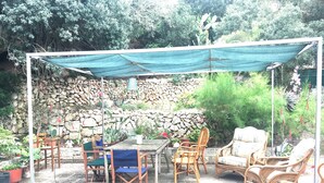An outdoor patio with a table and chairs, a stone wall, and various plants. - charming house (Villacarlos)