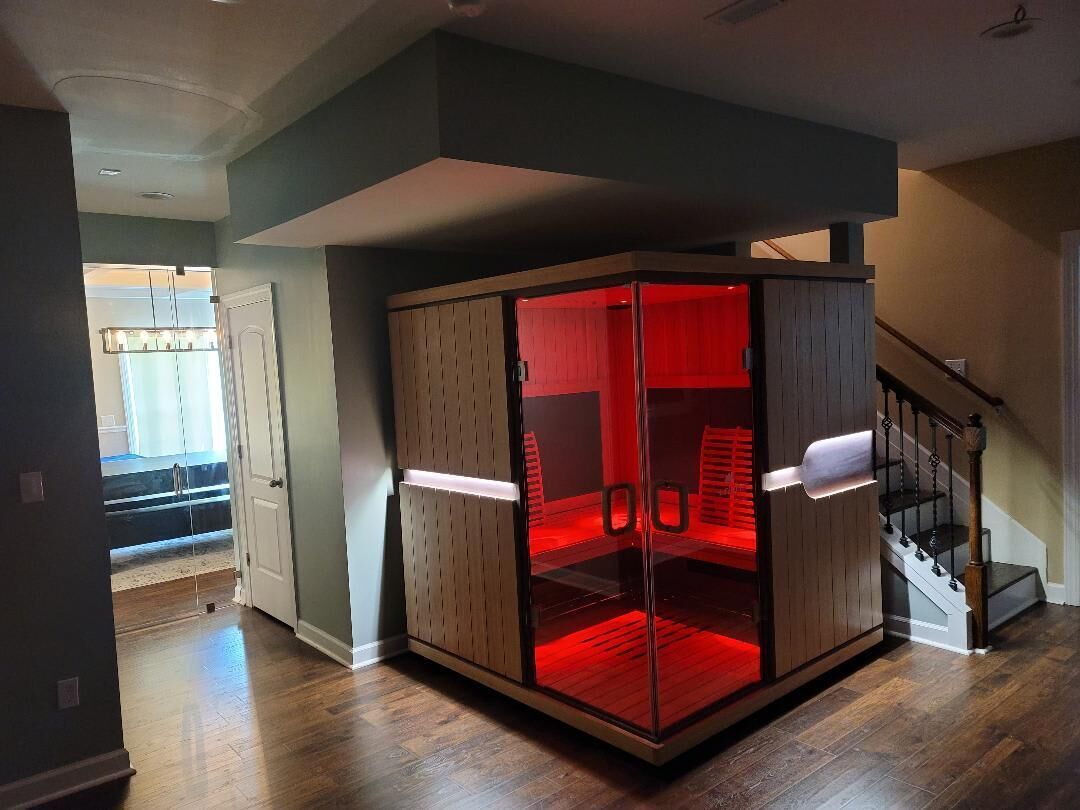 A corner room with a glass partition, a staircase, and a view of the adjacent living area.