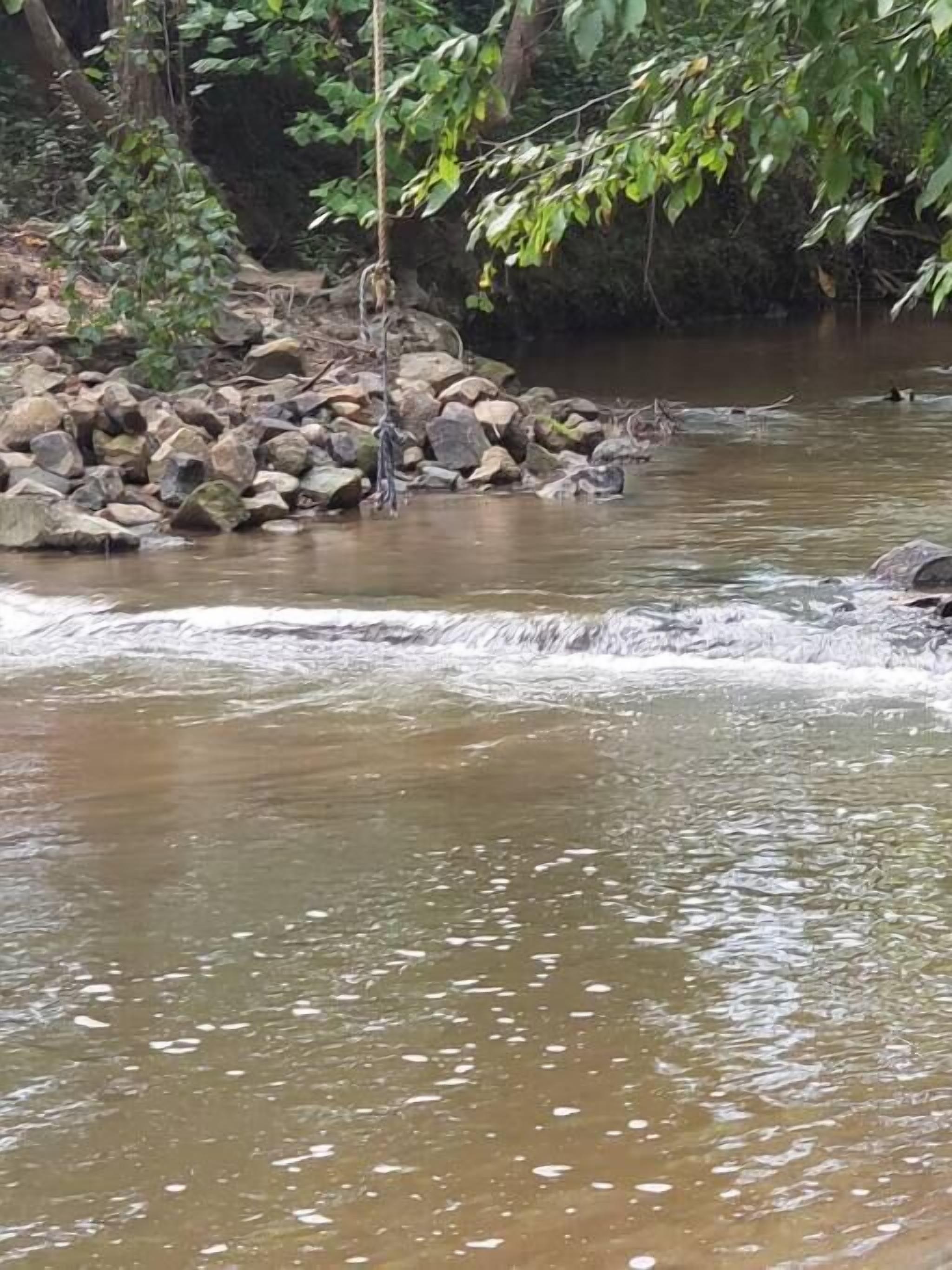 Ein Fluss fließt durch ein felsiges Gebiet mit einem kleinen Wasserfall.