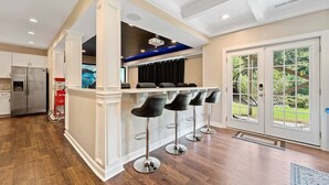 A modern kitchen with a bar area, stainless steel appliances, and a large window with a view of the outdoors.