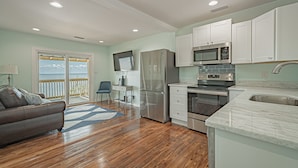 A modern kitchen with stainless steel appliances, a marble countertop, and a view to the outside. - Sunsets and Relaxation await -  Spot of Sun Bay Cottage (Gulf Shores)