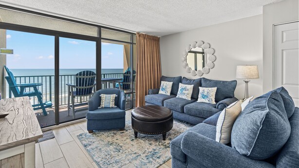 A living room with a large window, a sofa, a chair, and a coffee table.