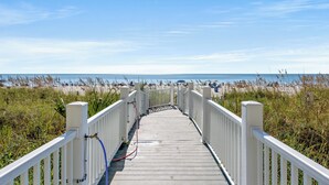 A wooden boardwalk leading to a beach with a clear sky.