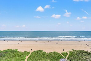 Une plage avec un ciel dégagé, des vagues et des gens.