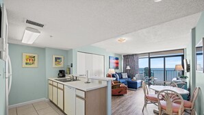 A compact living space with a kitchenette, dining area, and a balcony with a view.