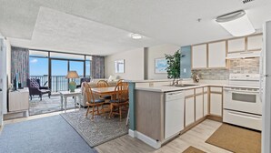 Une cuisine moderne avec un coin repas, de grandes fenêtres et une vue sur la mer.