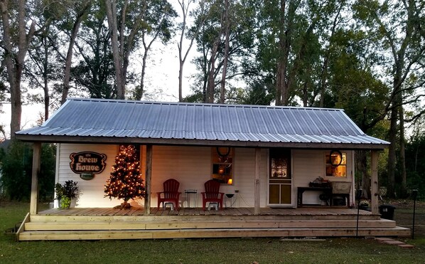 A rustic building with a corrugated metal roof, a Christmas tree, and outdoor seating.