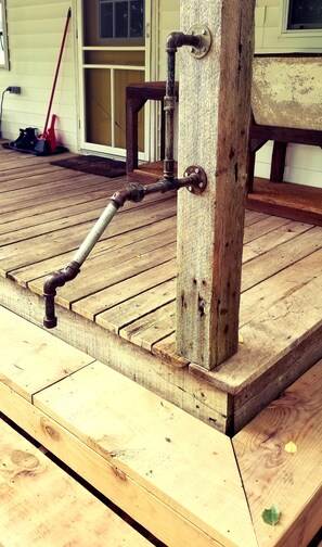 Una terraza de madera con un tubo de metal sujeto a un poste de madera.