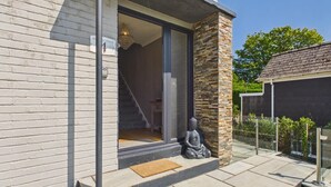 A modern house with a large glass door, a small statue, and a clear view of the interior. - Mayfield House - 4 Bedroom House - Tenby (Tenby)