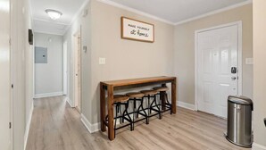 A hallway with a wooden bench and stools, a trash can, and a door.