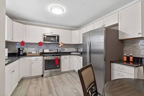Une cuisine moderne avec des armoires blanches, des appareils en acier inoxydable et un plancher en bois.