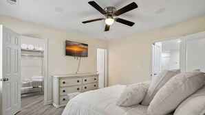 A bedroom with a bed, a dresser, a ceiling fan, and a painting on the wall. - 2BR Escape | Hot Tub | Parking 4 Cars | Pineville (Charlotte)
