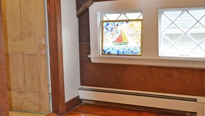 A room with a wooden door, a window with a stained glass design, and a patterned rug. - The Captain John Butman House (Rockport)