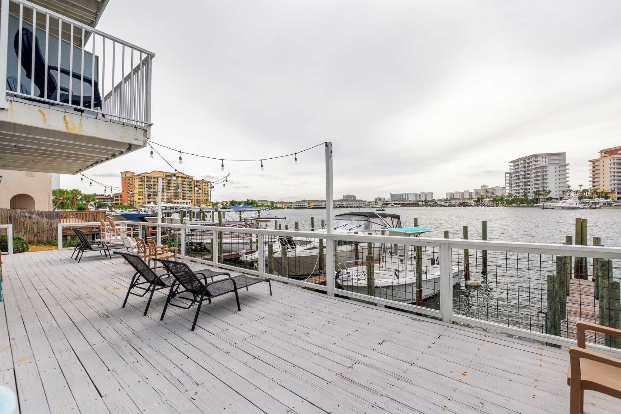 Eine Holzterrasse mit Sitzgelegenheiten mit Blick auf eine Marina und dort liegende Boote.