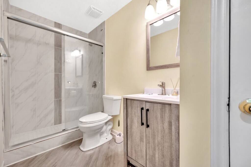 Une salle de bain moderne avec une douche à parois de verre, des toilettes et un meuble-lavabo avec un miroir.