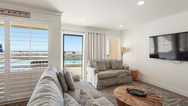 A modern living room with a sofa, a coffee table, and a TV mounted on the wall.