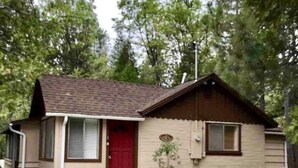 A single-story house with a red front door, a small porch, and a garage. - Bear’s Lair Cabin, Willow Cove, Bass Lake (Bass Lake)