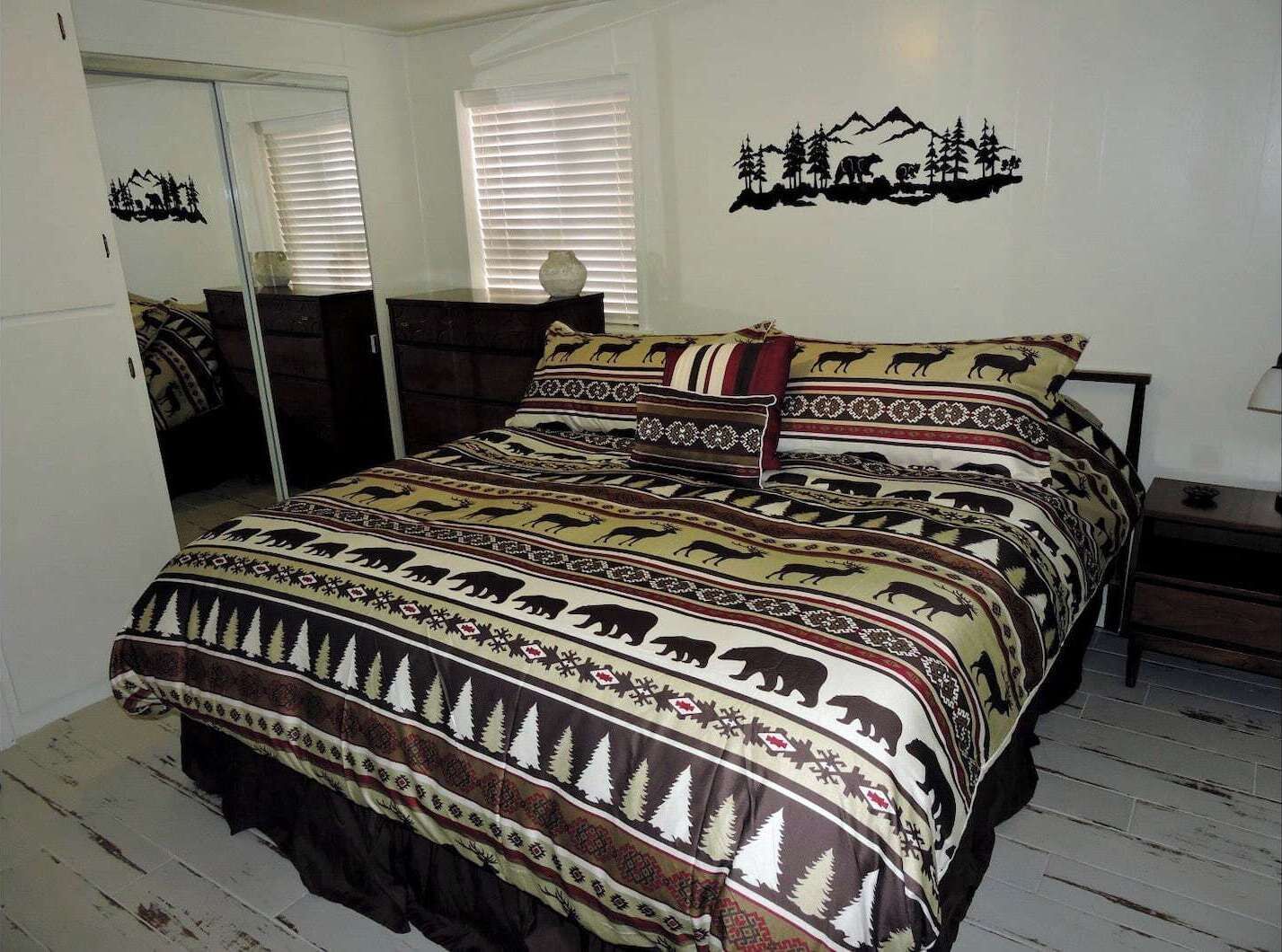 Een bed met beddengoed met patroon, een nachtkastje en een wanddecoratie.
