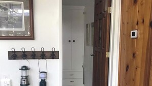 A hallway with a wooden door, a coat rack with hooks, and a small statue. - Bear’s Lair Cabin, Willow Cove, Bass Lake (Bass Lake)