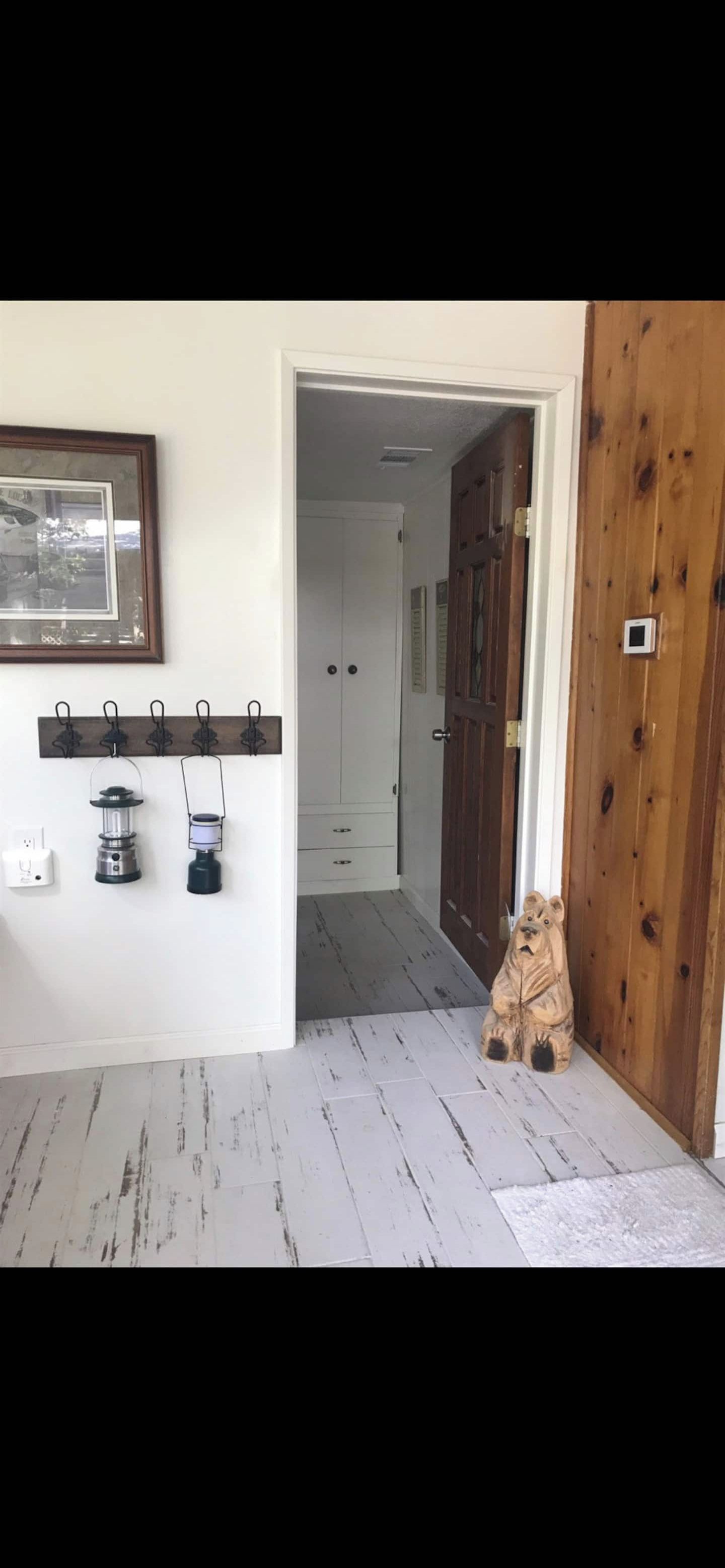 A hallway with a wooden door, a coat rack with hooks, and a small statue. - Bear’s Lair Cabin, Willow Cove, Bass Lake (Bass Lake)